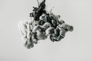 close up view of mixing of light gray and black paints splashes in water isolated on gray