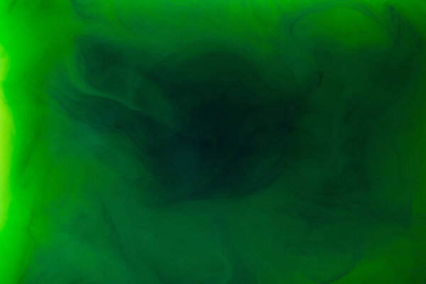 full frame image of mixing of green and black paints splashes in water isolated on gray