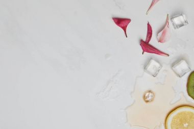 düz lay çiçek yaprakları, buz küpleri, limon ve kivi ile üzerinde beyaz masa üstü adet
