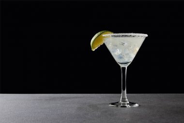 close up view of tasty margarita cocktail with lime and ice on tabletop on black clipart