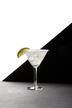 Close up view of tasty margarita cocktail with lime and ice on tabletop on black and white backdrop clipart