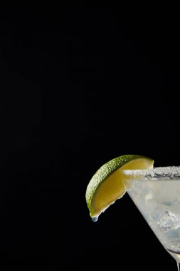 Close up view of cold margarita cocktail with lime isolated on black clipart