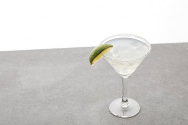close up view of refreshing alcohol margarita cocktail with lime and ice on tabletop on white clipart