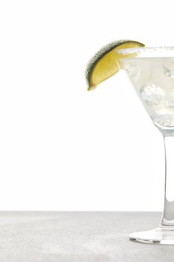 close up view of refreshing margarita cocktail with lime piece and ice on tabletop on white clipart