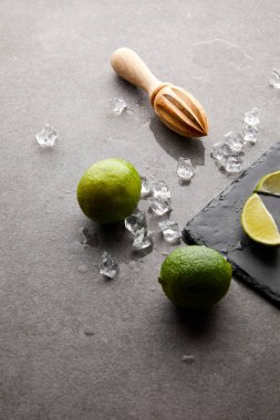 kokteyl için ahşap sıkacağı, limes ve buz küpleri görünümü gri yüzeyi kadar kapatın