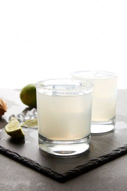 Close up view of refreshing caipirinha cocktails with lime on tabletop on white clipart