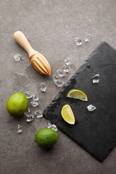 Flat Lay Wooden Squeezer Limes Ice Cubes Cocktail Grey Surface — Free Stock Photo