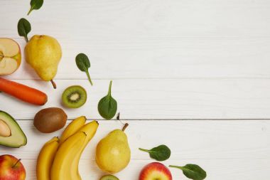 Beyaz ahşap arka planda kopya alanı ile üstten görünüm taze meyve ve ıspanak yaprakları