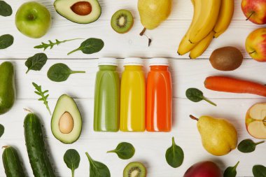 flat lay with bottles with detox smoothies in row with fruits and vegetables on wooden background clipart