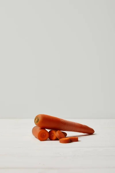 fresh juicy carrots on white wooden surface