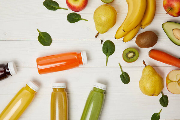 top view of fresh fruits and bottles with smoothies on wooden background 