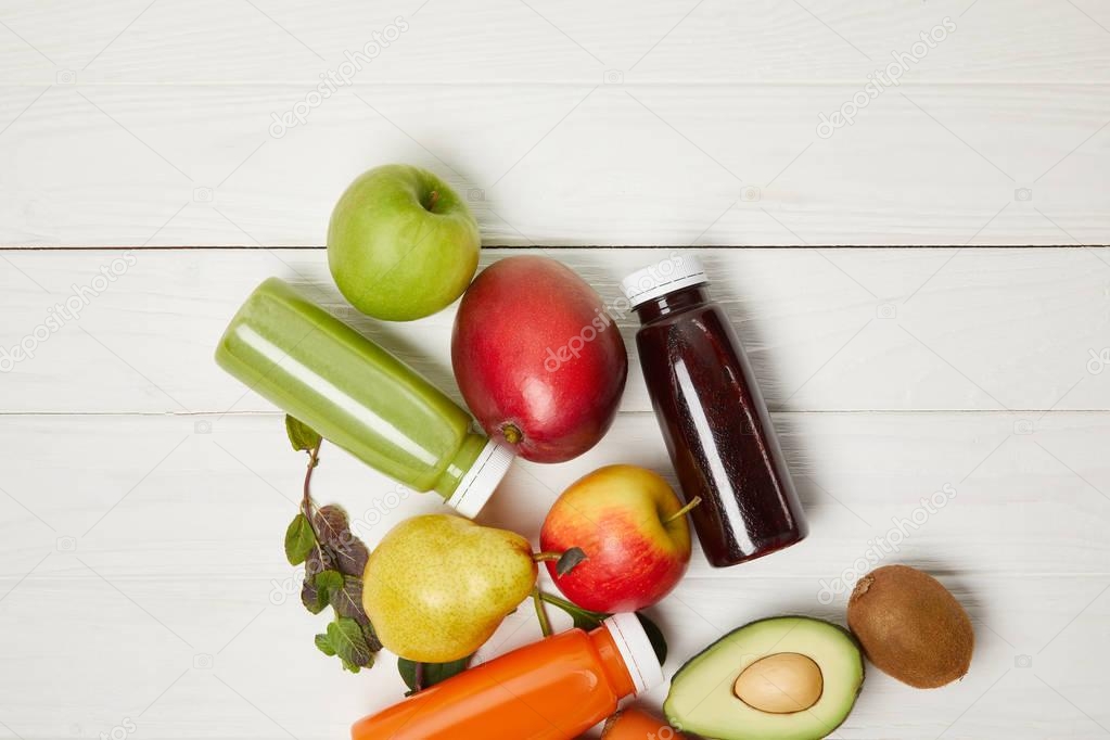 top view of fresh fruits and detox smoothies on white wooden background  
