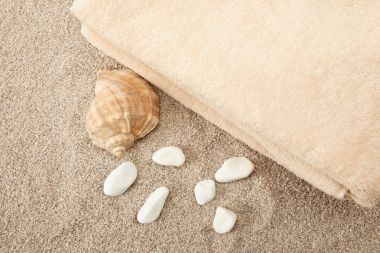 top view of seashell, sea stones and towels on sand clipart