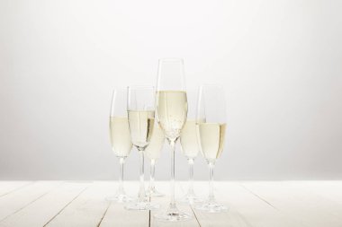closeup view of champagne glasses on white wooden table  clipart