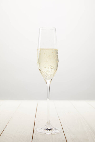 closeup view of champagne glass with bubbles on white wooden table 