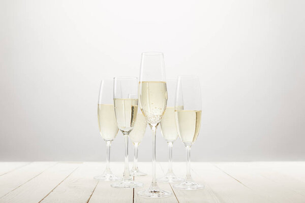 closeup view of champagne glasses on white wooden table 