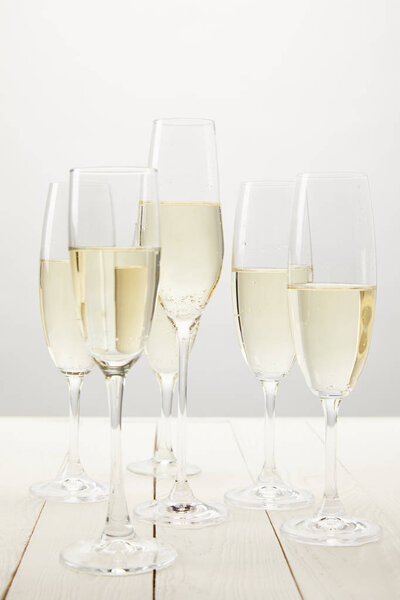 closeup view of champagne glasses on white wooden table 