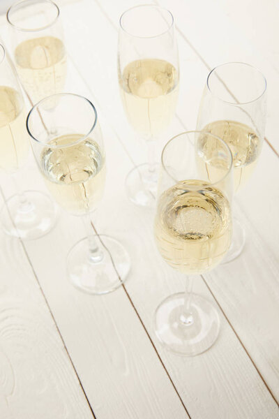 high angle view of champagne glasses on white wooden table 