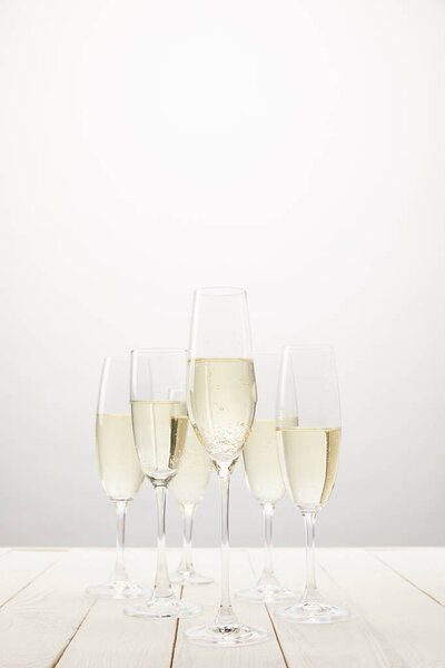 closeup view of champagne glasses on white wooden table 