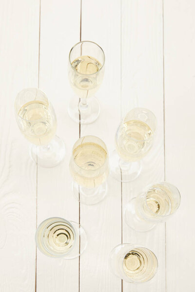 top view of champagne glasses on white wooden table 