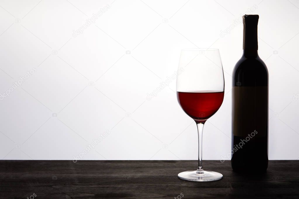 bottle and glass with red wine on dark wooden table 