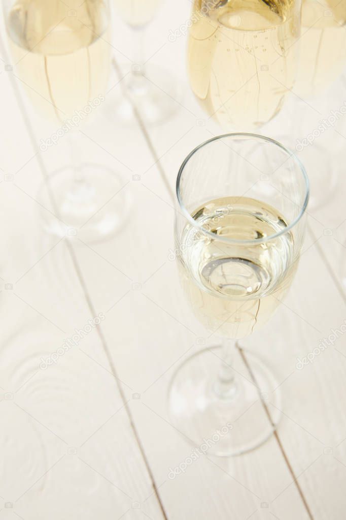 high angle view of champagne glasses on white wooden table 