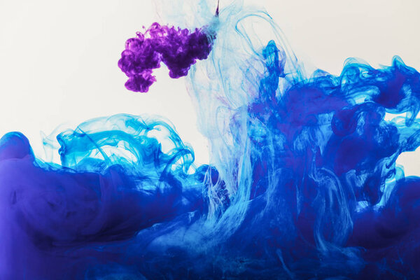 texture with flowing blue and purple paint in water, isolated on white