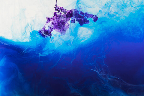 creative background with flowing blue and purple paint in water