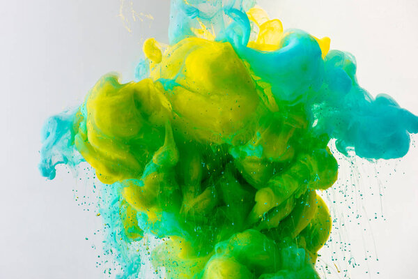 artistic background with flowing turquoise, yellow and green paint in water, isolated on grey