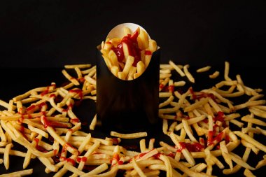 patates kızartması siyah siyah izole masa üzerinde dağınık patates kızartması ile çevrili kutusunda