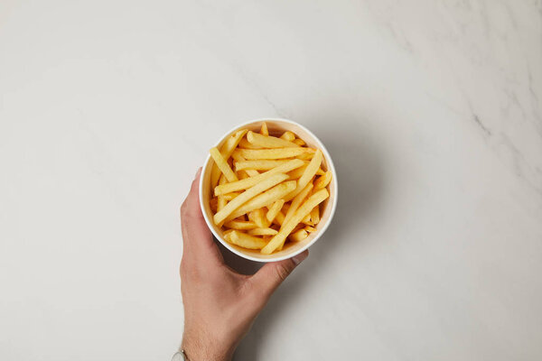 cropped shot of man holding bowl of delicious french fries on white
