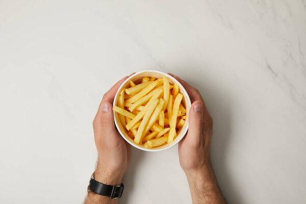 cropped shot of man holding bowl of french fries on white