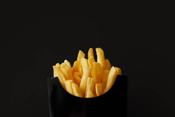 close-up shot of black box of delicious french fries isolated on black