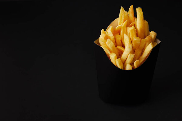 black box of tasty french fries isolated on black isolated on black