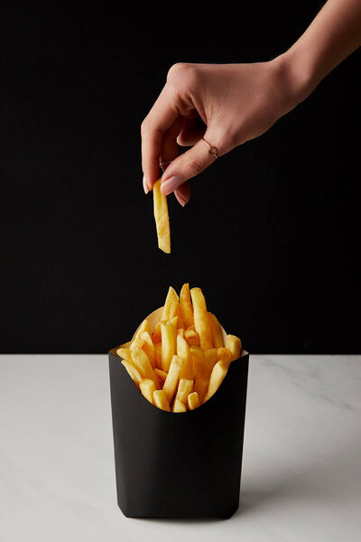 woman taking out french fry from box isolated on black