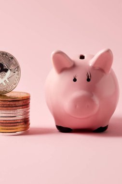 bitcoins ve kumbara pembe masa üzerinde yığınının yakın çekim vurdu