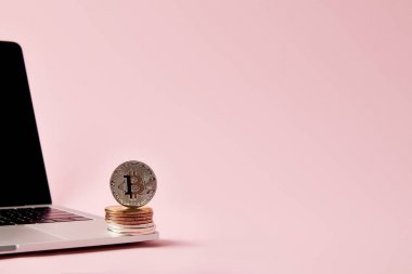 bitcoins laptop pembe yüzey üzerinde yığılmış