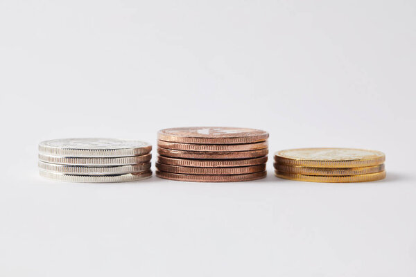 крупным планом стопки золотых, серебряных и бронзовых биткойнов на белом
