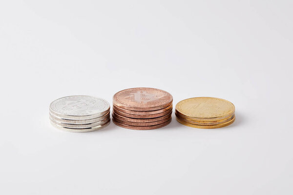 стопки золотых, серебряных и бронзовых биткойнов на белом
