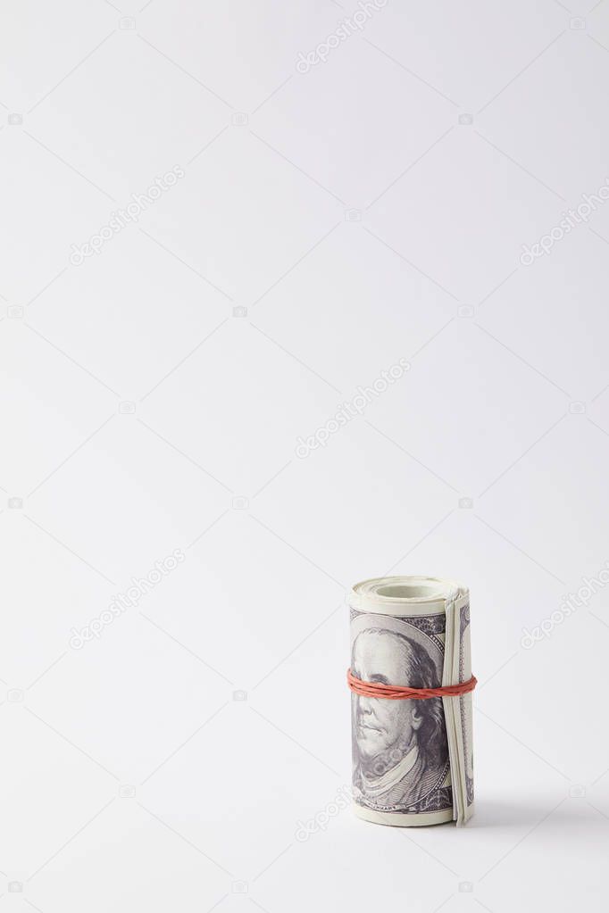 roll of dollars tied with red rubber band on white