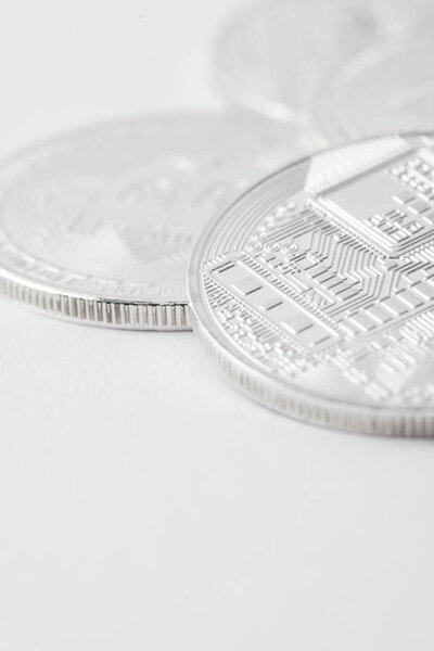 close-up shot of pile of silver bitcoins on white tabletop