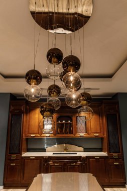 Shiny spherical chandelier over elegant wooden counter in kitchen clipart