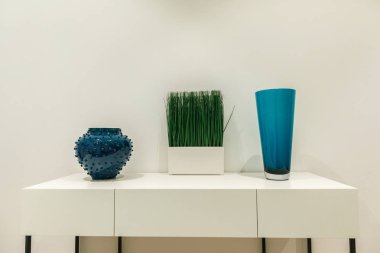 Mavi vazolar ve çim duvar tarafından beyaz masa üzerinde