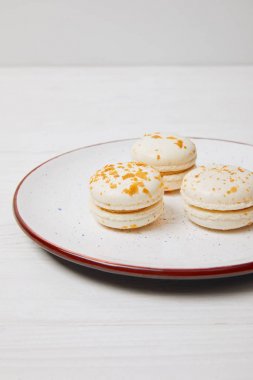 Üç macarons plaka üzerinde beyaz ahşap masa 