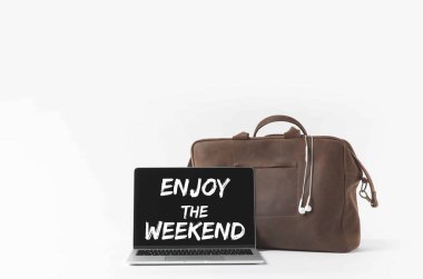 laptop with Enjoy the weekend lettering on screen and stylish bag with earphones, isolated on white clipart