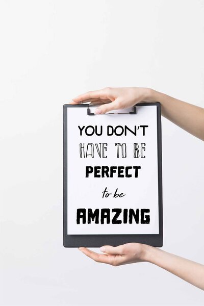 partial view of woman holding clipboard with "You dont have to be perfect to be Amazing" inspiration, isolated on white 