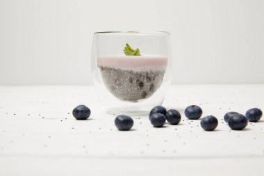 close up view of chia seed pudding with mint leaves and fresh blueberries on white tabletop clipart