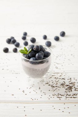 tatlı chia tohum puding yaban mersini ve nane ile bakış beyaz ahşap yüzey üzerinde kapatın