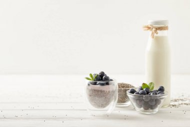 Beyaz ahşap yüzeyde chia puding ve maddeler görünümü kadar kapatın