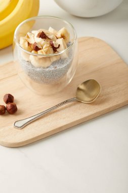 lezzetli chia tohum puding muz ve fındık parçaları ile bakış ahşap kesme tahtası üzerinde kaşıkla kapatın